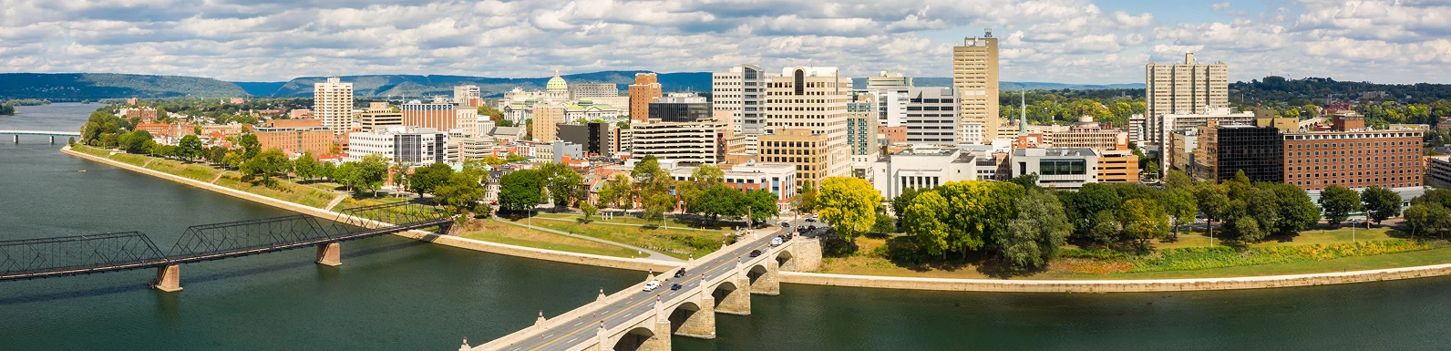 A skyline of tall buildings alongside a flowing river in an urban setting